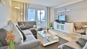 A modern living room with a sofa, coffee table, and TV. - Seebrücke Appartement 2 - Seebrücke (Scharbeutz)