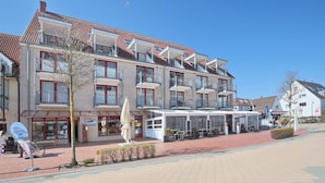 A multi-story hotel with balconies, a covered outdoor seating area, and a clear blue sky. - Seebrücke Appartement 2 - Seebrücke (Scharbeutz)