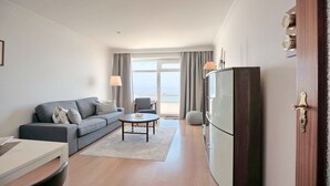 A modern living room with a grey sofa, a round coffee table, and a flat-screen TV.