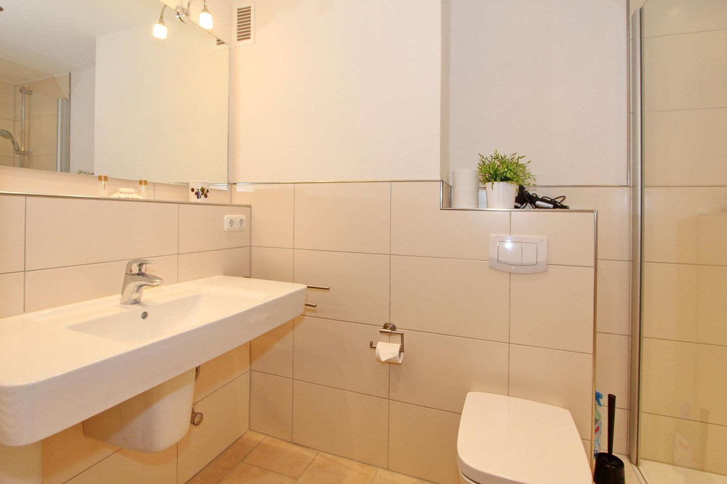 A modern bathroom with a large sink, a toilet, and a shower area.