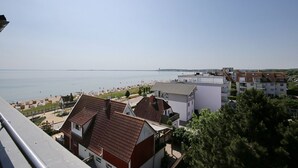 A coastal residential area with buildings, a beach, and a clear view of the sea. - Strandperle Apartment 403 - Strandperle (Scharbeutz)