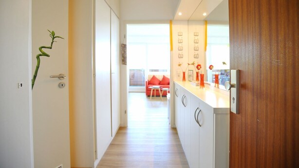 A modern kitchen with a wooden countertop, a built-in oven, and a window overlooking the dining area. - Strandperle Apartment 403 - Strandperle (Scharbeutz)