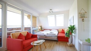 A bright room with a red sofa, a bed, and a glass coffee table. - Strandperle Apartment 403 - Strandperle (Scharbeutz)