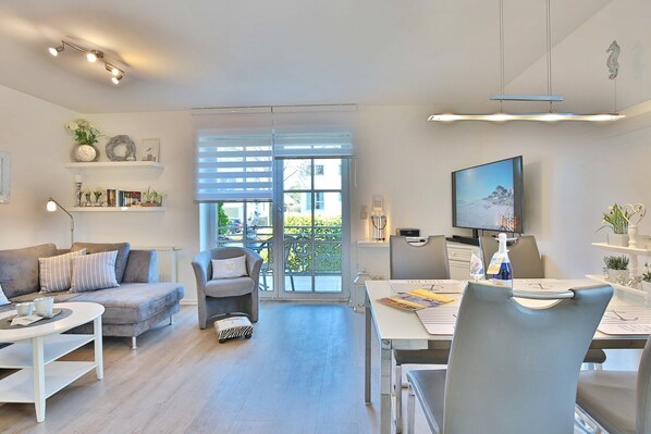 A modern living room with a sofa, armchairs, a dining table, and a TV.