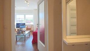A modern living room with a television, a glass coffee table, and a red sofa.