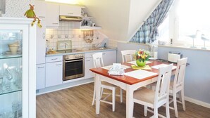 A modern kitchen with white cabinets, a built-in oven, and a dining area with a wooden table and chairs.