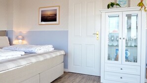 A bedroom with a bed, a bedside lamp, a wardrobe with glass doors, and a framed picture on the wall.
