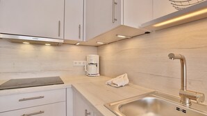 Une cuisine moderne avec des meubles blancs, un évier en acier inoxydable et une machine à café intégrée.