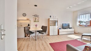 Un salon moderne comprenant un coin repas, un téléviseur et une fenêtre avec des rideaux.