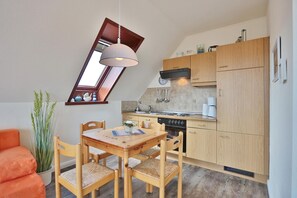 Una cocina compacta con comedor, armarios de madera, estufa y un ventanal pequeño.