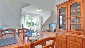 A dining area with a wooden table, chairs, and a cabinet with glass doors. - Terraced house Eichenweg - Terraced house Eichenweg Apartment 8 (Scharbeutz)