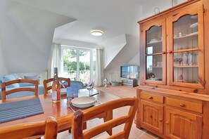 Un comedor con una mesa de madera, sillas y un armario con puertas de vidrio.