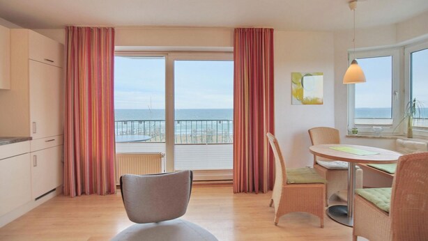 Une chambre moderne avec balcon, une table à manger et vue sur la mer.