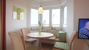 Un coin repas accueillant avec des chaises en osier, une table ronde et une suspension.