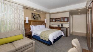 Een hotelkamer met een bed, een bureau, een stoel en een bank.