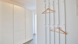 A hallway with a white wardrobe and a wall-mounted wooden hanger rack. - Strandschlösschen Appartement 5 - Strandschlößchen (Scharbeutz)