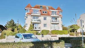 A multi-story residential building with a red-tiled roof, balconies, and a white picket fence. - Strandschlösschen Appartement 5 - Strandschlößchen (Scharbeutz)