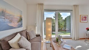 En stue med sofa, sofabord og et maleri på væggen.