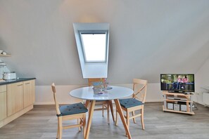 A compact living space with a kitchen, dining area, and a television. - Barque Apartment 404 - Barque (Scharbeutz)