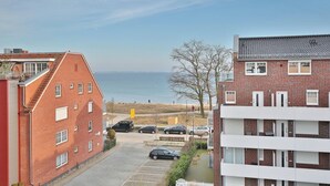 A residential building with a view of the sea, featuring a parking area and a pathway leading to the beach. - Barque Apartment 404 - Barque (Scharbeutz)