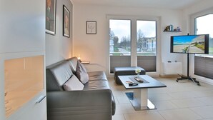 Ein modernes Wohnzimmer mit grauem Sofa, Couchtisch und Flachbildfernseher.