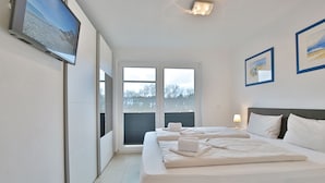 Ein Hotelzimmer mit zwei Betten, einem Fernseher und einem Fenster mit Jalousien.