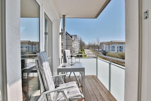 A balcony with a table and chairs, a view of buildings, and a railing. - Strandglück Apartment 14C - Strandglück Haus C (Scharbeutz)