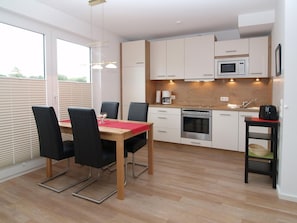 Una cocina moderna con armarios blancos, encimera de madera, horno empotrado y microondas.