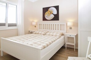 A neatly arranged bedroom with a bed, bedside tables, and a wall-mounted lamp.