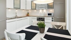 A modern kitchen with white cabinetry, a central island, and a pendant light. - Strandglück Apartment 17C - Strandglück House C (Scharbeutz)