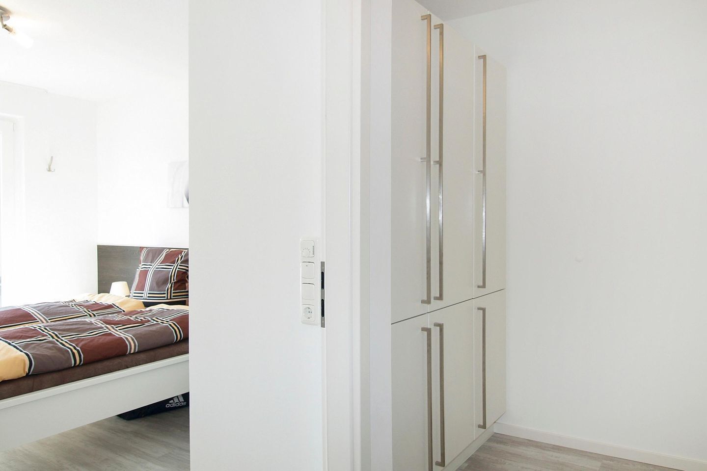 Een slaapkamer met een bed, een kledingkast en een nachtkastje.