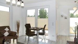 Uma sala de estar moderna com um sofá, uma mesa de jantar com cadeiras e uma garrafa de vinho.