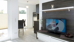 Cozinha moderna com televisão integrada, área de jantar e vista para o exterior.