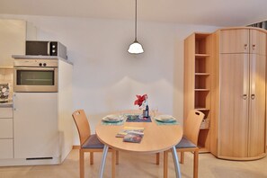 Una cocina compacta con microondas, horno y comedor con una mesa redonda y sillas.