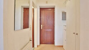 A narrow hallway with a wooden door at the end, white walls, and a radiator on the left. - Strandburg Apartment 2 - Strandburg (Scharbeutz)