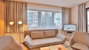 A modern living room with a sofa, two armchairs, a coffee table, a TV, and a floor lamp. - Strandburg Apartment 2 - Strandburg (Scharbeutz)