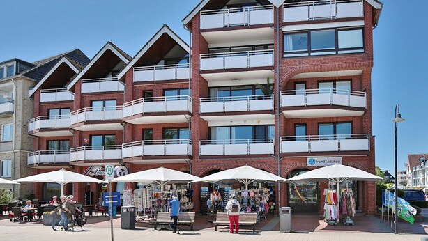 A multi-story building with balconies, outdoor seating, and a visible storefront. - Strandburg Apartment 2 - Strandburg (Scharbeutz)