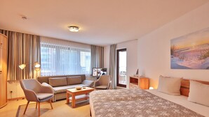 A hotel room with a large bed, a sofa, a chair, a small table, and a TV. - Strandburg Apartment 2 - Strandburg (Scharbeutz)