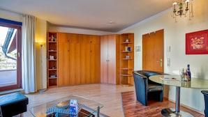 Een moderne woonkamer met een glazen salontafel, een leren bank, houten kasten en een kroonluchter.