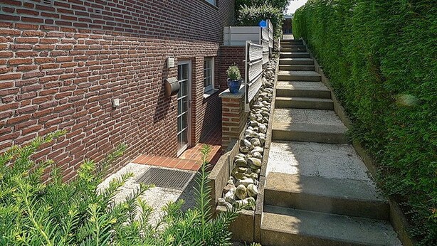 A brick building with a stone retaining wall and steps leading up to a gated entrance. - Sandpiper Apartment 2 - Sandpiper (Scharbeutz)