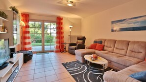 A modern living room with a sofa, TV, and a small table with a candle. - Sandpiper Apartment 2 - Sandpiper (Scharbeutz)