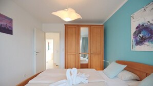Une chambre d’hôtel avec un lit, une armoire en bois, un tableau au mur et un luminaire.