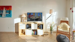 Un salon avec un téléviseur, une bibliothèque et un fauteuil.