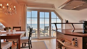 Eine moderne Küche mit Meerblick, ein Essbereich mit Stühlen und eine Kristallleuchter.