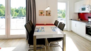 A modern kitchen with a dining table, chairs, and a microwave. - Strandglück, Apartment 8c - Strandglück House B (Scharbeutz)