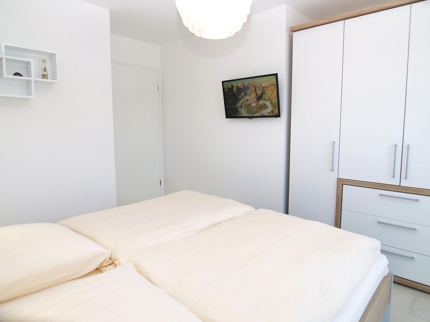 A bedroom with a bed, a wardrobe, a painting, and a shelf with bottles.