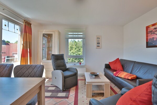 A modern living room with a sofa, armchair, and dining table.