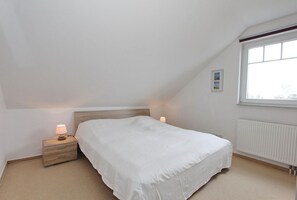 A bedroom with a single bed, a nightstand with a lamp, a window with a view, and a radiator. - Feriendomizil am Konsulweg Apartment 7 - Feriendomizil am Konsulweg (Scharbeutz)