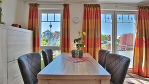 Un comedor con una mesa de madera, cuatro sillas y vistas al exterior a través de amplios ventanales.