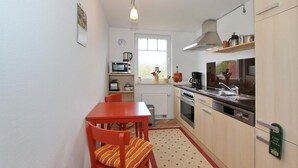 Una cocina compacta con una mesa de comedor, sillas, microondas, cafetera y un lavabo.